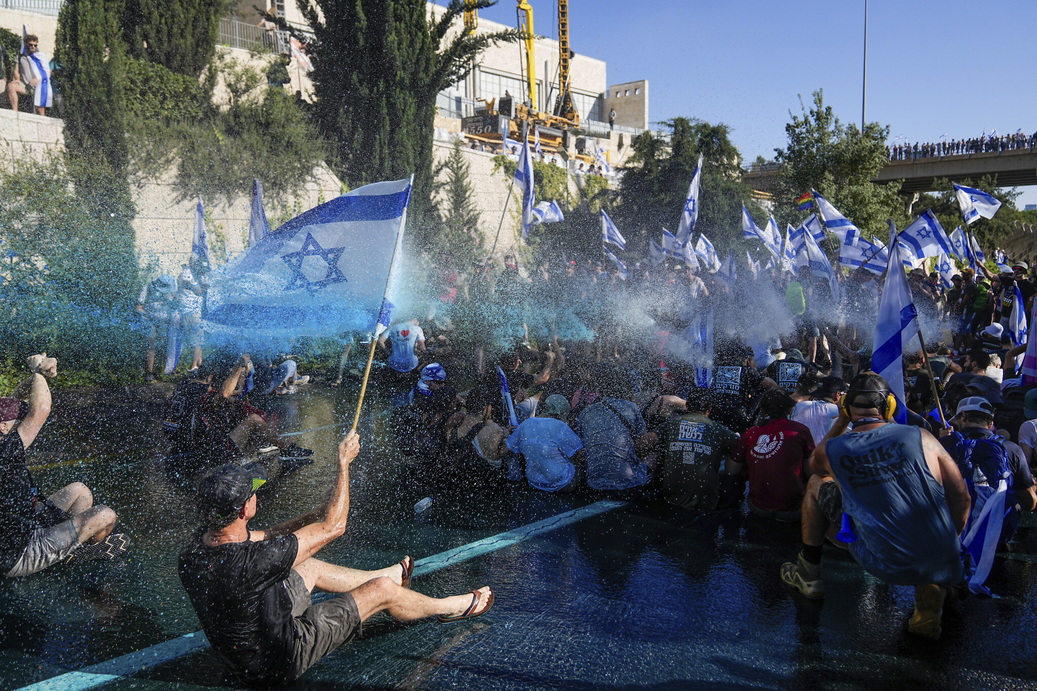 La police israélienne utilisant un canon à eau pour disperser les manifestants qui bloquent une route lors d'une manifestation contre les mesures prises par le gouvernement du Premier ministre Benjamin Netanyahu pour réformer le système judiciaire, à Jérusalem, le 24 juillet 2023. (Crédit : Ohad Zwigenberg/AP Photo)