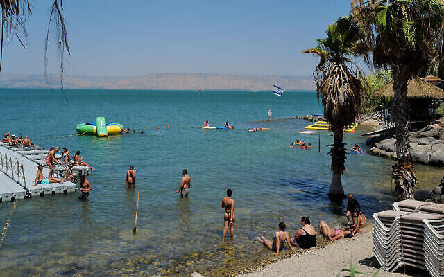 Des Israéliens et des touristes se rafraîchissant dans le lac de Tibériade, le 28 juin 2023. (Crédit : Michael Giladi/Flash90)