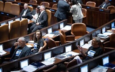 Les députés de Yesh Atid portant des tee-shirts noirs ornés de drapeaux israéliens lors des délibérations en plénum sur le projet de loi du "caractère raisonnable", à la Knesset, le 10 juillet 2023. (Crédit : Yonatan Sindel/Flash90)