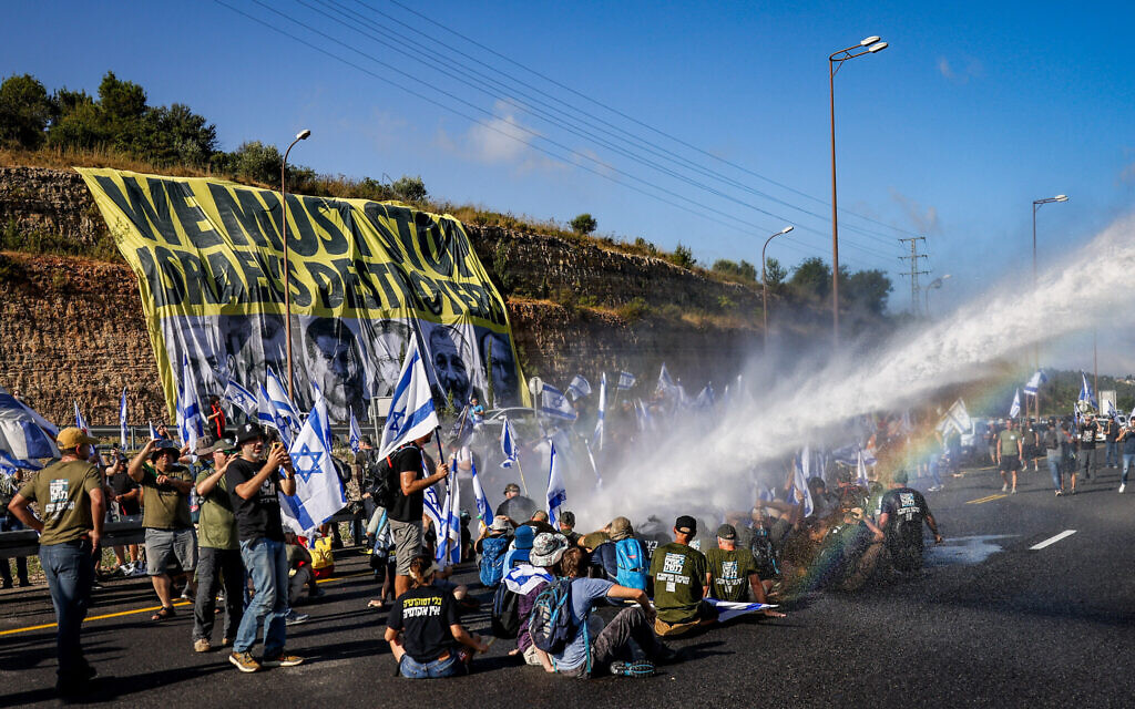 Des manifestants contre la refonte judiciaire bloquant une route et se heurtant à la police lors d'une manifestation contre la refonte judiciaire sur la Route 1, près d'Ein Hemed, le 11 juillet 2023. (Crédit : Chaïm Goldberg/Flash90)