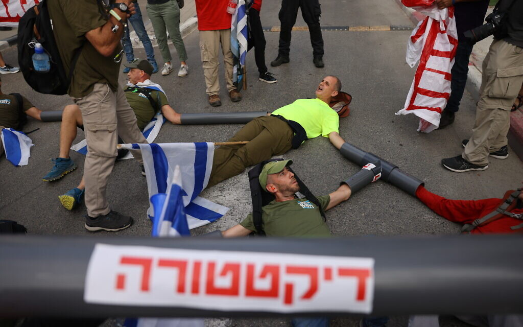 Des manifestants contre la refonte du système judiciaire bloquant une entrée du ministère de la Défense, à Tel Aviv, le 18 juillet 2023. (Crédit : Chaïm Goldberg/Flash90)