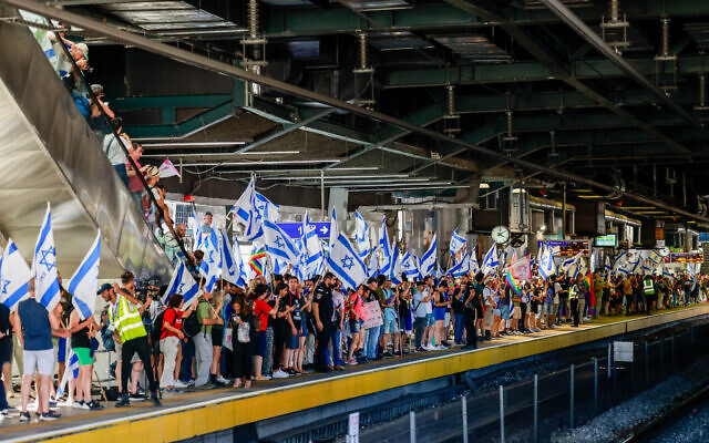 Des Israéliens protestent contre la réforme judiciaire du gouvernement à la gare Hashalom de Tel Aviv, le 18 juillet 2023. (Crédit : Chaim Goldberg/Flash90)