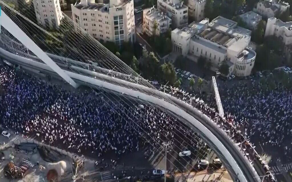 Des dizaines de milliers de manifestants entrant dans Jérusalem, au terme d'une marche de plusieurs jours qui a débuté à Tel Aviv pour protester contre la loi de réforme judiciaire du gouvernement avant le vote de la première loi de ce type à la Knesset, sous le pont des accords à l'entrée de la capitale, le 22 juillet 2023. (Crédit :  Capture d'écran de la Treizième chaîne ; utilisée conformément à l'article 27a de la loi sur le droit d'auteur)