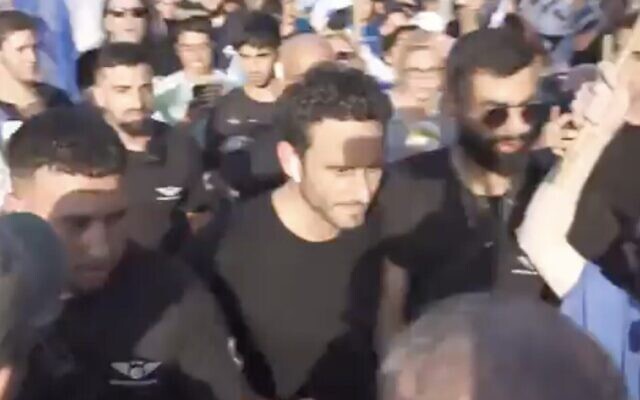 La police escortant le journaliste de la Douzième chaîne, Gilad Shalmor, lors d'une manifestation en faveur de la refonte, à Tel Aviv, le 23 juillet 2024. (Crédit : Twitter ; utilisée conformément à la clause 27a de la loi sur le droit d'auteur)