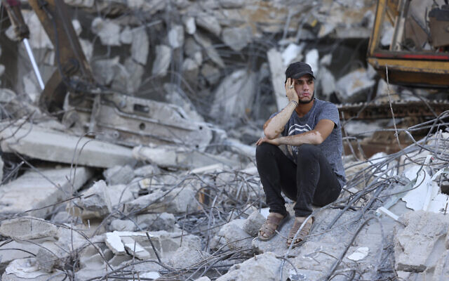 Un Palestinien est assis sur les décombres d'un bâtiment détruit par des frappes aériennes israéliennes dans la ville de Gaza, le 15 juin 2021. (Crédit : MOHAMMED ABED / AFP / File)