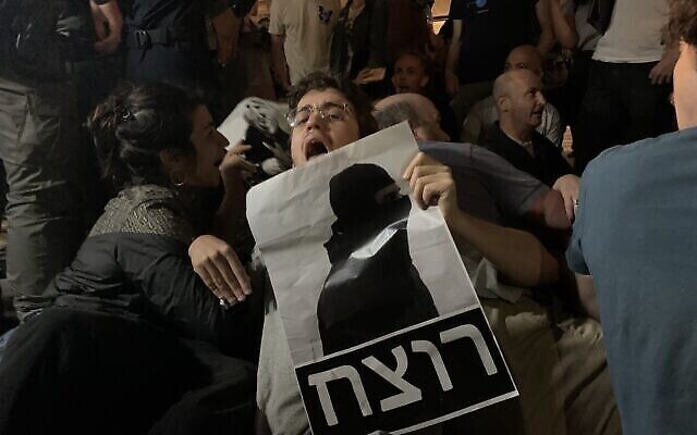 Un manifestant à Jérusalem tient une pancarte revêtue du mot « Meurtrier » en hébreu, et qui représente la silhouette du policier acquitté de la mort d'Iyad Halak, en 2020. (Crédit : Charlie Summers/Times of Israel)