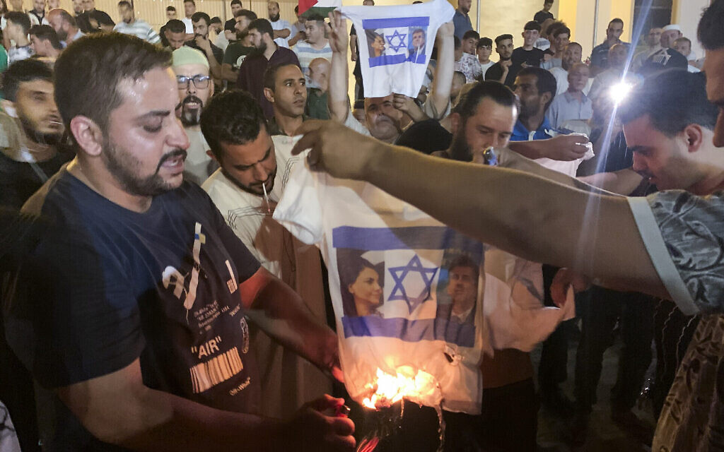 Des Libyens brûlent une chemise montrant un drapeau israélien, le ministre des Affaires étrangères Eli Cohen et son homologue libyen Najla Mangoush, à Tripoli, en Libye, le 27 août 2023. (Crédit : Yousef Murad/AP)