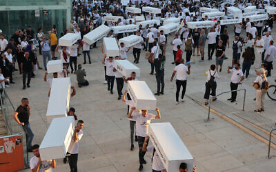 Des manifestants défilant avec des cercueils symboliques pour dénoncer  les crimes violents commis contre les communautés arabes, dans la ville côtière israélienne de Tel Aviv, le 6 août 2023. (Crédit : Jack Guez/AFP)