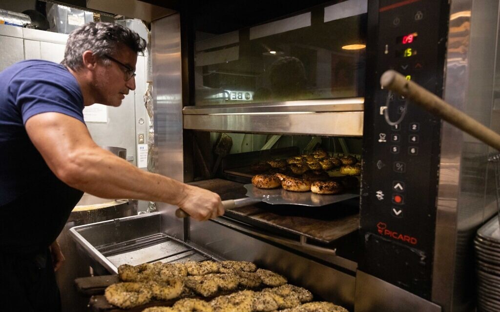 Andrew Martinez, propriétaire de Bo's Bagels, faisant cuire des bagels dans le four de son magasin, à  à New York, le 12 juillet 2023. (Crédit : Yuki Iwamura/AFP)
