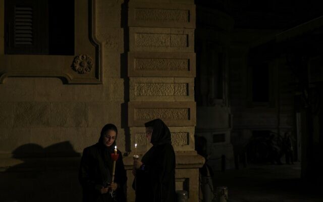 Des nonnes chrétiennes orthodoxes avec des bougies et des fleurs à la main lors d'une procession vers le tombeau où la vierge Marie serait inhumée, dans la Vieille Ville de Jérusalem, pour la fête de l'Assomption, le 25 août 2023. (Crédit : RONALDO SCHEMIDT / AFP)