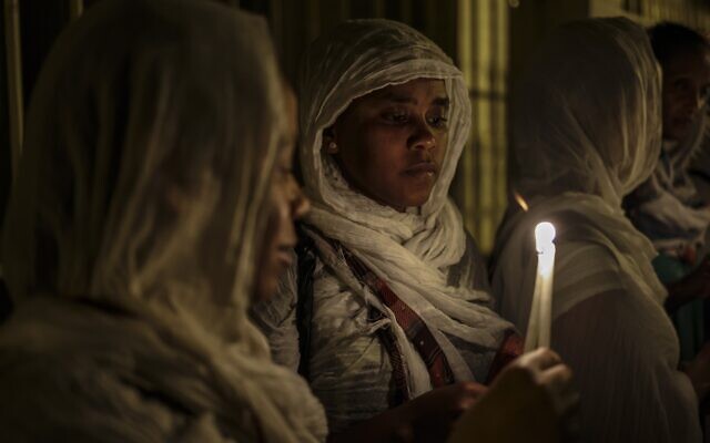 Des nonnes chrétiennes orthodoxes éthiopiennes avec des bougies et des fleurs à la main lors d'une procession vers le tombeau où la vierge Marie serait inhumée, dans la Vieille Ville de Jérusalem, pour la fête de l'Assomption, le 25 août 2023.  (Crédit : RONALDO SCHEMIDT / AFP)