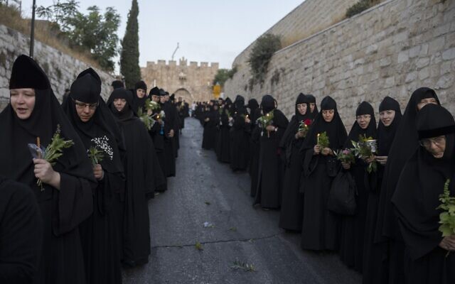 Des nonnes chrétiennes orthodoxes avec des bougies et des fleurs à la main lors d'une procession vers le tombeau où la vierge Marie serait inhumée, dans la Vieille Ville de Jérusalem, pour la fête de l'Assomption, le 25 août 2023.  (Crédit : : MENAHEM KAHANA / AFP)