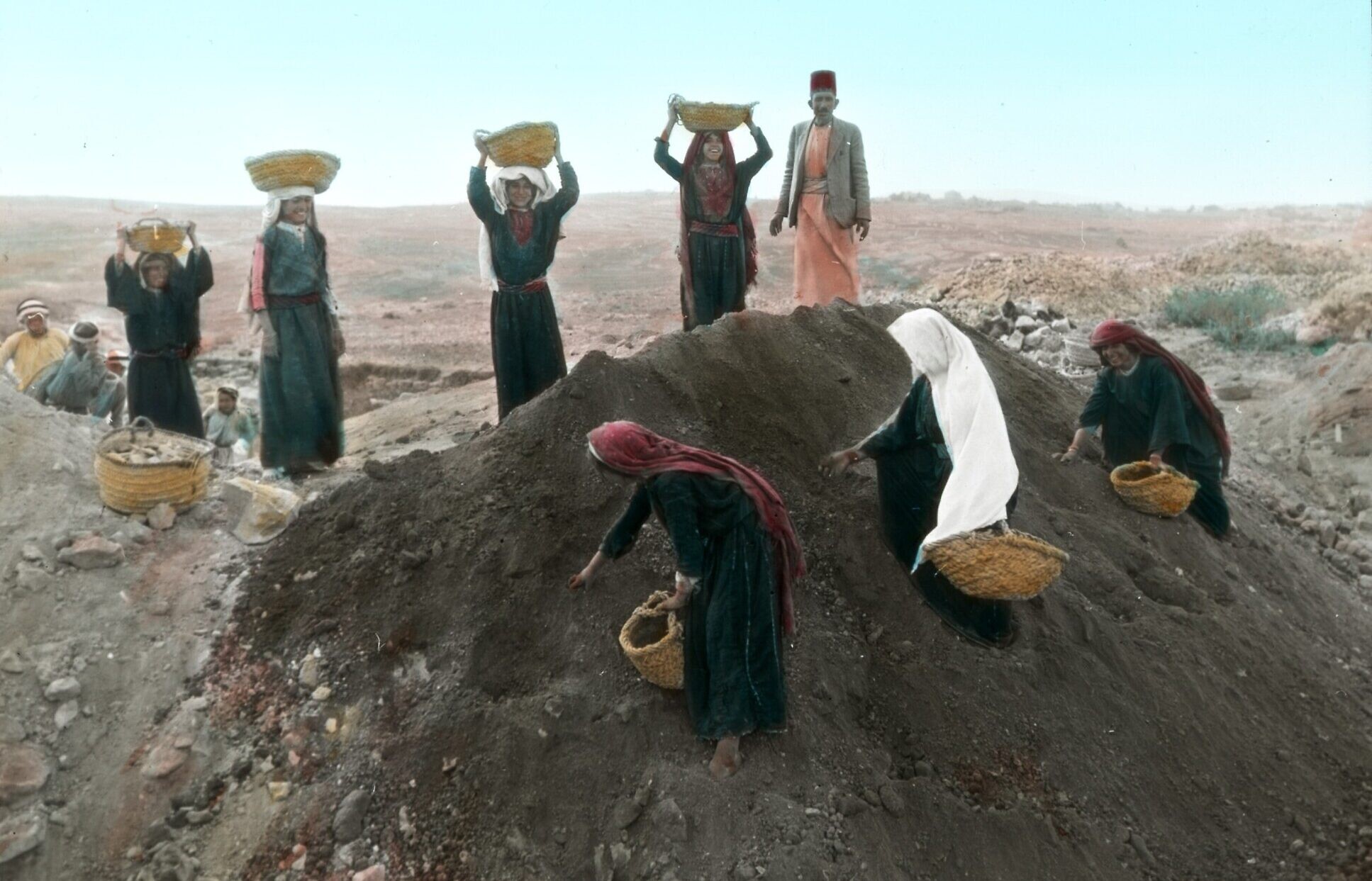Des femmes transportant des paniers de terre excavée vers la décharge de Tell en-Naṣbeh, tandis que d'autres ramassent des tessons de poterie dans le monticule de terre, en 1935. (Crédit : Musée Badè/École de religion du Pacifique)