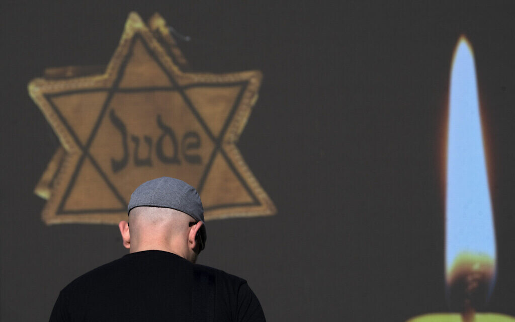 Illustration : Un homme passant devant un panneau d'affichage montrant une étoile de David jaune sur laquelle on peut lire "Jude", "Juif" en allemand. (Crédit : Oded Balilty/AP Photo)