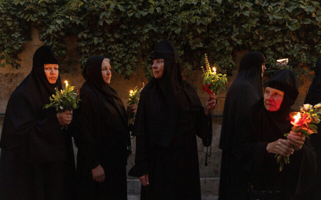 Des nonnes chrétiennes orthodoxes avec des bougies et des fleurs à la main lors d'une procession vers le tombeau où la vierge Marie serait inhumée, dans la Vieille Ville de Jérusalem, pour la fête de l'Assomption, le 25 août 2023.  (Crédit : AP/Ohad Zwigenberg)