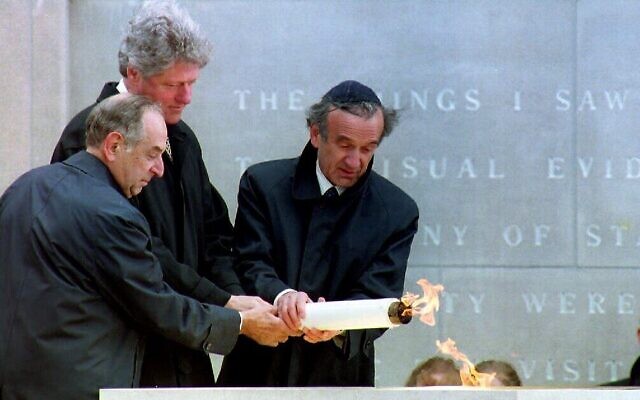 Le président américain Bill Clinton, au centre, allumant la flamme éternelle avec l'aide du président du Conseil du mémorial Harvey Meyerhoff, à gauche, et du président fondateur Elie Wiesel, à droite, au mémorial de la Shoah des États-Unis, le 22 avril 1993. (Crédit :  Renaud Giroux/AFP)