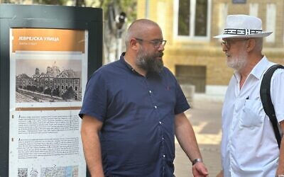 Ladislav Trajer, à gauche, et Mirko Štark, les deux principaux dirigeants de la communauté juive de Novi Sad, en Serbie, discutent juste devant l'entrée de leur synagogue. (Crédit : Larry Luxner/JTA)