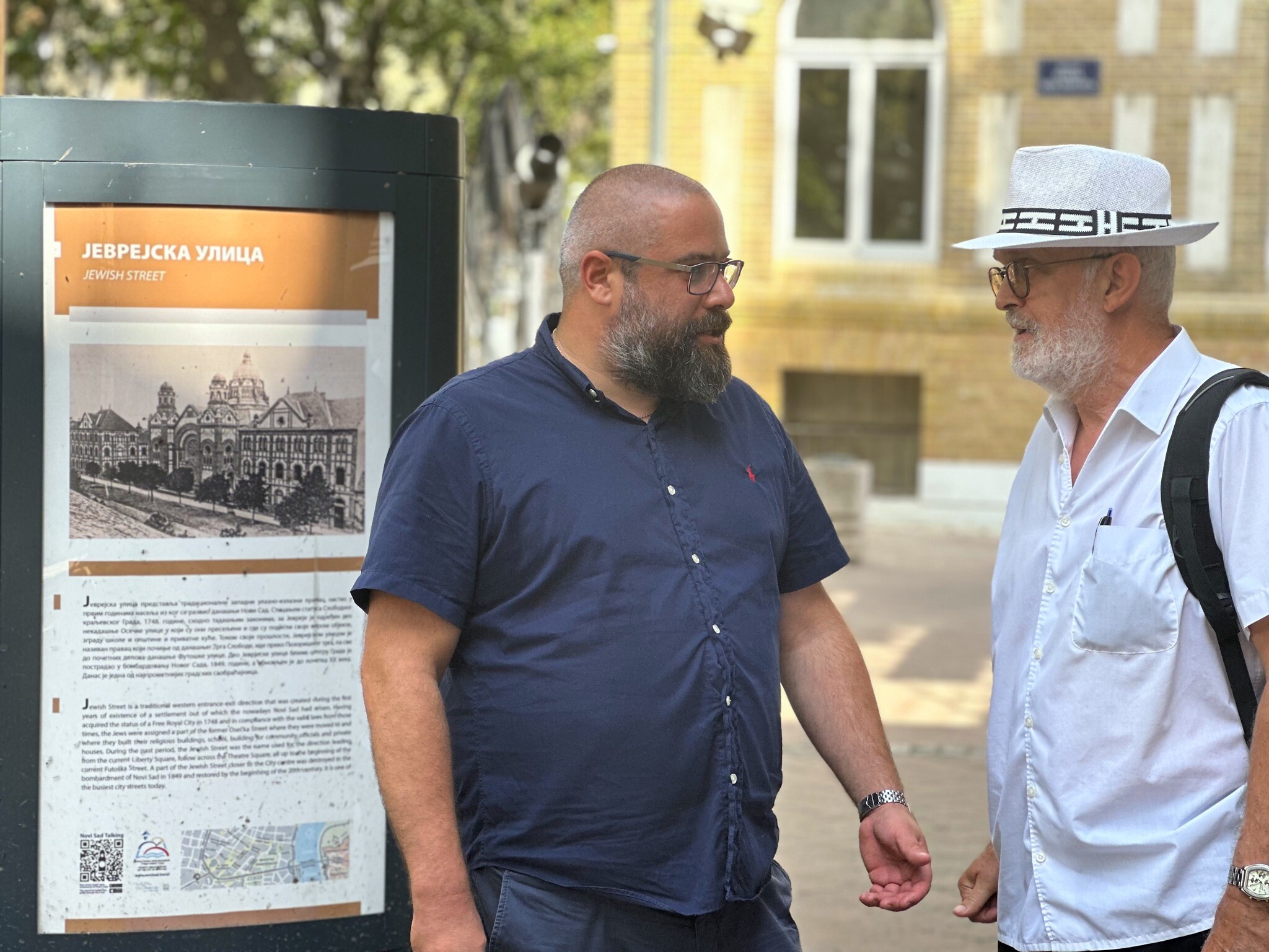 Ladislav Trajer, à gauche, et Mirko Štark, les deux principaux dirigeants de la communauté juive de Novi Sad, en Serbie, discutent juste devant l'entrée de leur synagogue. (Crédit : Larry Luxner/JTA)