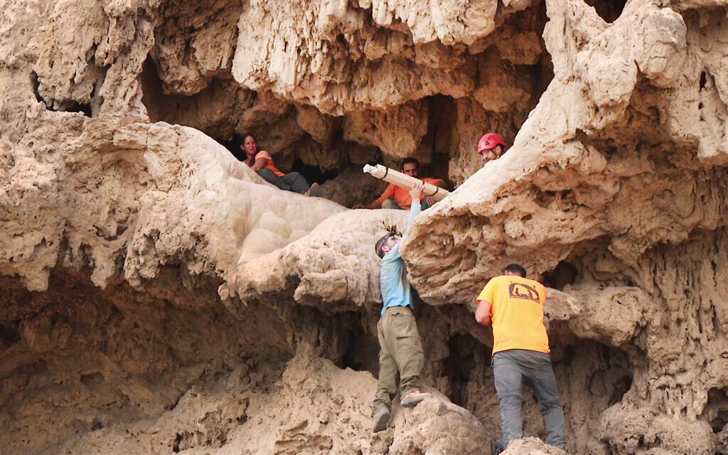 Des archéologues retirant avec précaution les épées de l'entrée de la grotte où elles ont été découvertes dans le désert de Judée. (Crédit : Emil Aladjem/IAA)