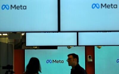 Des visiteurs devant et à côté d'écrans affichant le logo Meta lors d'un événement au siège social de Meta à Berlin le 6 juin 2023. (Crédit : Tobias Schwarz/AFP)