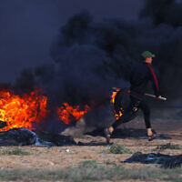Un émeutier palestinien brûle des pneus lors d'affrontements avec des soldats israéliens à l'est de Rafah, dans le sud de la bande de Gaza, près de la barrière frontalière entre Israël et Gaza, le 23 septembre 2023. (Crédit : SAID KHATIB / AFP)