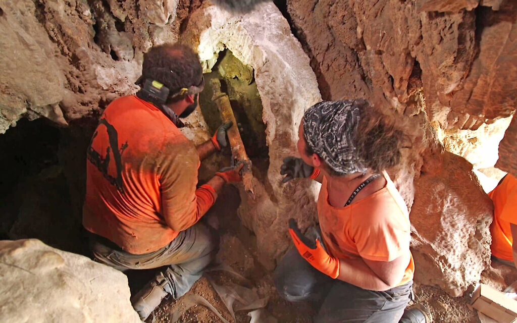 Des archéologues retirant les épées de l'anfractuosité de la roche où elles ont été cachées il y a environ 1 900 ans dans une grotte du désert de Judée. (Crédit : Emil Aladjem/IAA)