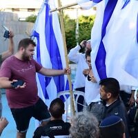 Des militants laïcs enlèvent une barrière de cloison séparant les hommes et les femmes, faite de drapeaux israéliens, installée par le groupe Rosh Yehudi au mépris d'une ordonnance de la Haute Cour, lors d'une prière publique sur la place Dizengoff, à Tel-Aviv, le jour de Yom Kippour, le 24 septembre 2023. (Crédit : Tomer Neuberg/Flash90)