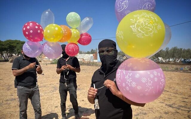 Des Gazaouis masqués se préparent à lancer des ballons incendiaires depuis l'enclave côtière en direction d'Israël, le 23 septembre 2023. (Crédit : Réseaux sociaux palestiniens)