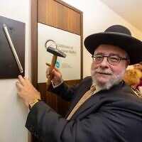 Pinchas Goldschmidt, le président de la Conférence des rabbins européens, apposant une mezuzah sur le cadre de la porte du Centre pour la vie juive, à Munich, en Allemagne, le 19 septembre 2023. (Crédit : Conférence des rabbins européens)