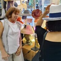 Dalia Varman (à gauche) regarde une cliente essayer un chapeau, dans sa boutique Les Chapeaux de Dalia, à Tel Aviv. (Crédit : Gavriel Fiske/Times of Israel)