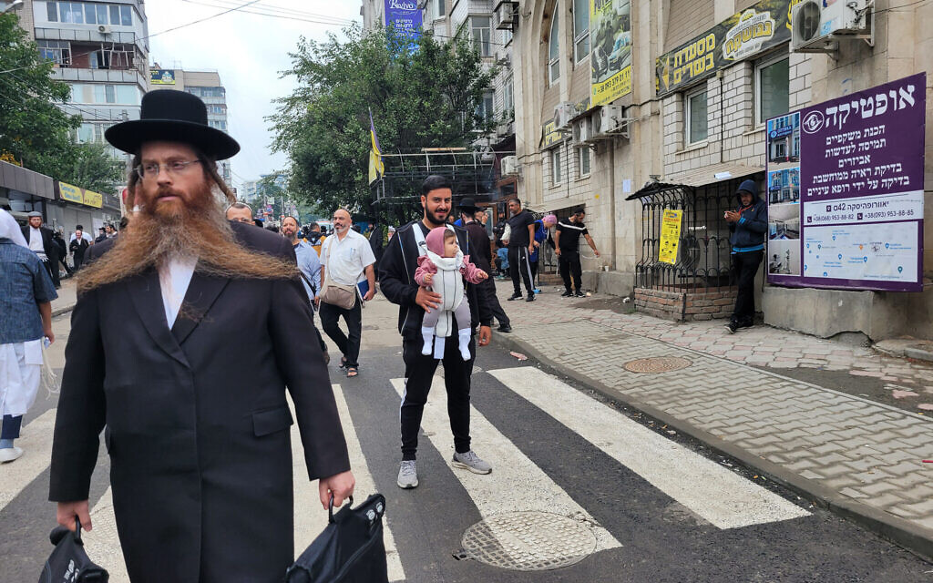Un pèlerin israélien marchant avec sa fille à Ouman, en Ukraine, le 15 septembre 2023. (Crédit : Canaan Lidor/Times of Israel)