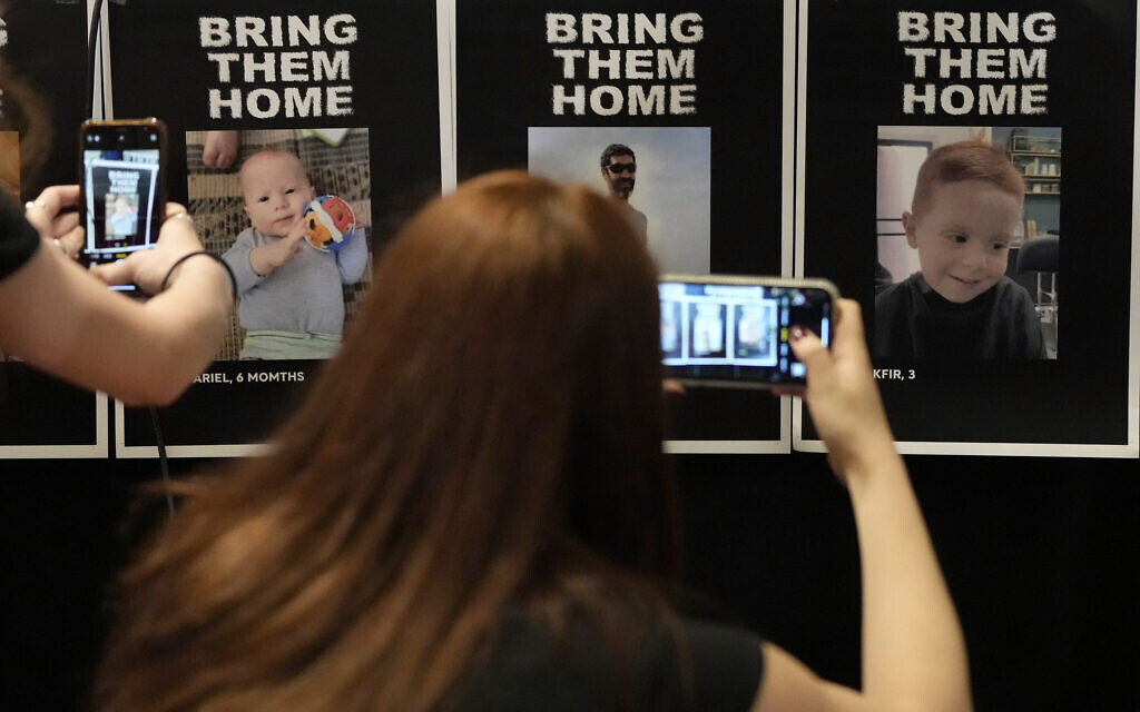 Des journalistes photographient des affiches de personnes disparues avant une conférence de presse sur les otages israéliens, parmi lesquels se trouvent des Britanniques, dans un hôtel de Londres, le 12 octobre 2023. (Crédit : AP/Kirsty Wigglesworth)