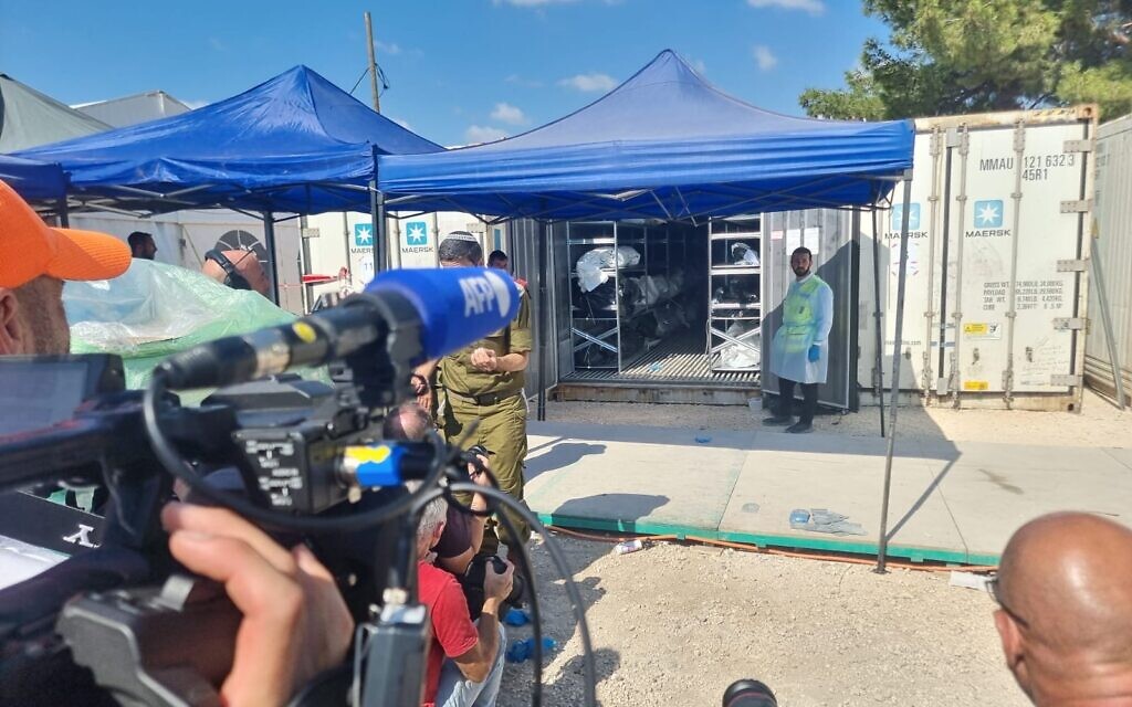 Un volontaire de Zaka devant des conteneurs servant de morgue temporaire pour les victimes de l'attaque du Hamas du 7 octobre, au siège du rabbinat militaire à Ramle, le 13 octobre 2023. (Crédit : GPO)