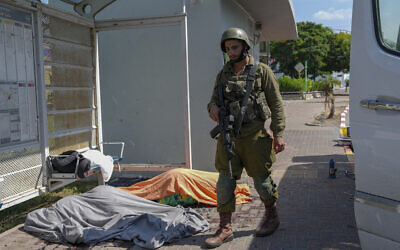 Un soldat israélien près des dépouilles d'Israéliens tués par des terroristes palestiniens venus de la bande de Gaza, dans la ville de Sderot, dans le sud d'Israël, le samedi 7 octobre 2023. (Crédit : Tsafrir Abayov/AP)