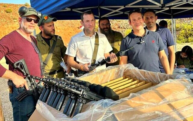Le chef du Conseil de Samarie, Yossi Dagan, aide à distribuer des fusils d'assaut aux escouades de sécurité civiles dans les implantations du nord de la Cisjordanie, le 22 octobre 2023. (Crédit : Roi Hadi)