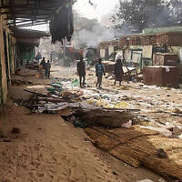 Des personnes marchent parmi des objets éparpillés, alors que les combats se poursuivent au Soudan entre les forces de deux généraux rivaux , marché d'El Geneina, la capitale du Darfour occidental, le 29 avril 2023. (Crédit : AFP)