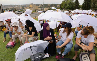 Des activistes de diverses ONG locales et étrangères rassemblées autour du monument de la tolérance dans un parc de Jérusalem, alors qu'elles participent à un événement conjoint organisé par les mouvements israélien Women Wage Peace et palestinien Women of the Sun, demandant la fin du cycle de l'effusion de sang et une solution au conflit israélo-palestinien, le 4 octobre 2023. (Crédit : Menahem Kahana/AFP)