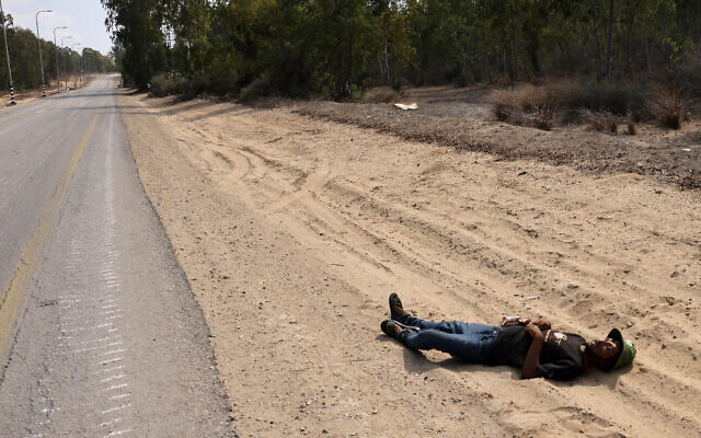 Le cadavre d'un terroriste palestinien gisant le long d'une route dans un lieu non divulgué à la frontière avec la Bande de Gaza, le 8 octobre 2023. (Crédit : Menahem Kahana/AFP)