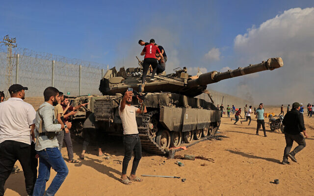 Des Palestiniens prenant le contrôle d'un char israélien après avoir franchi la barrière frontalière avec Israël depuis Khan Yunis, dans le sud de la Bande de Gaza, le 7 octobre 2023. (Crédit : Saïd Khatib/AFP)