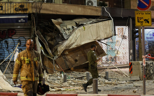 Un pompier marchant devant un magasin endommagé à Tel Aviv, après qu'il a été touché par une roquette tirée par des terroristes palestiniens depuis la Bande de Gaza, le 7 octobre 2023. (Crédit : Jack Guez/AFP)