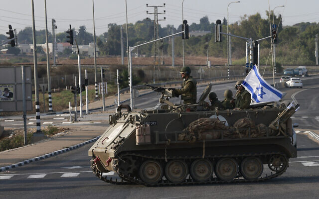 Des forces israéliennes traversant une route principale dans un véhicule blindé de transport de troupes (APC) alors que des troupes supplémentaires sont déployées près de la ville de Sderot à la suite d'un assaut par des terroristes du Hamas, le 8 octobre 2023. (Crédit : Menahem Kahana/AFP)