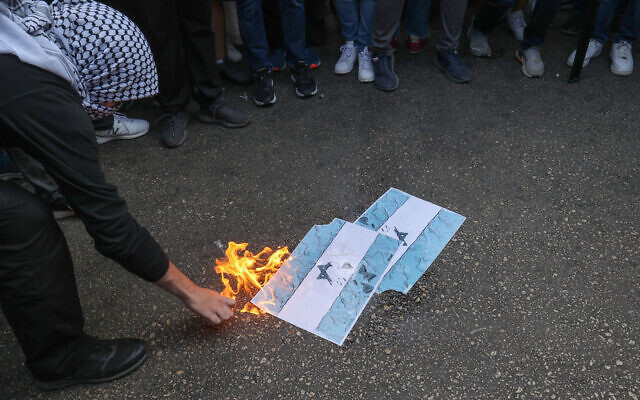 Des étudiants de l'Université américaine de Beyrouth (AUB) brûlent des drapeaux israéliens lors d'un rassemblement de soutien aux Palestiniens devant la porte principale de l'université dans la capitale libanaise, le 9 octobre 2023. (Crédit : ANWAR AMRO / AFP)