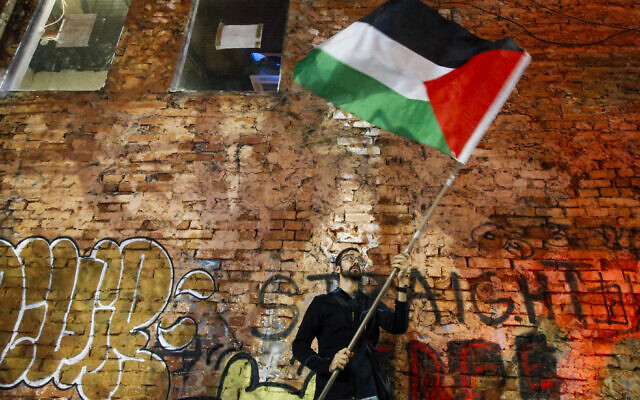 Un homme brandit un drapeau palestinien lors d'une manifestation à Sao Paulo, au Brésil, le 10 octobre 2023. (Crédit : Miguel SCHINCARIOL / AFP)