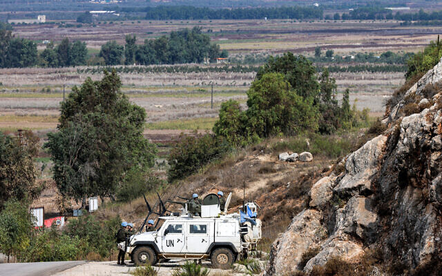 Un véhicule blindé de la Force intérimaire des Nations Unies au Liban (FINUL) stationné près d'un point frontalier dans la plaine de Khiyam au Liban, en face de la ville de Metula au nord d'Israël, en arrière-plan, le 11 octobre 2023. (Crédit : Joseph Eid/AFP)