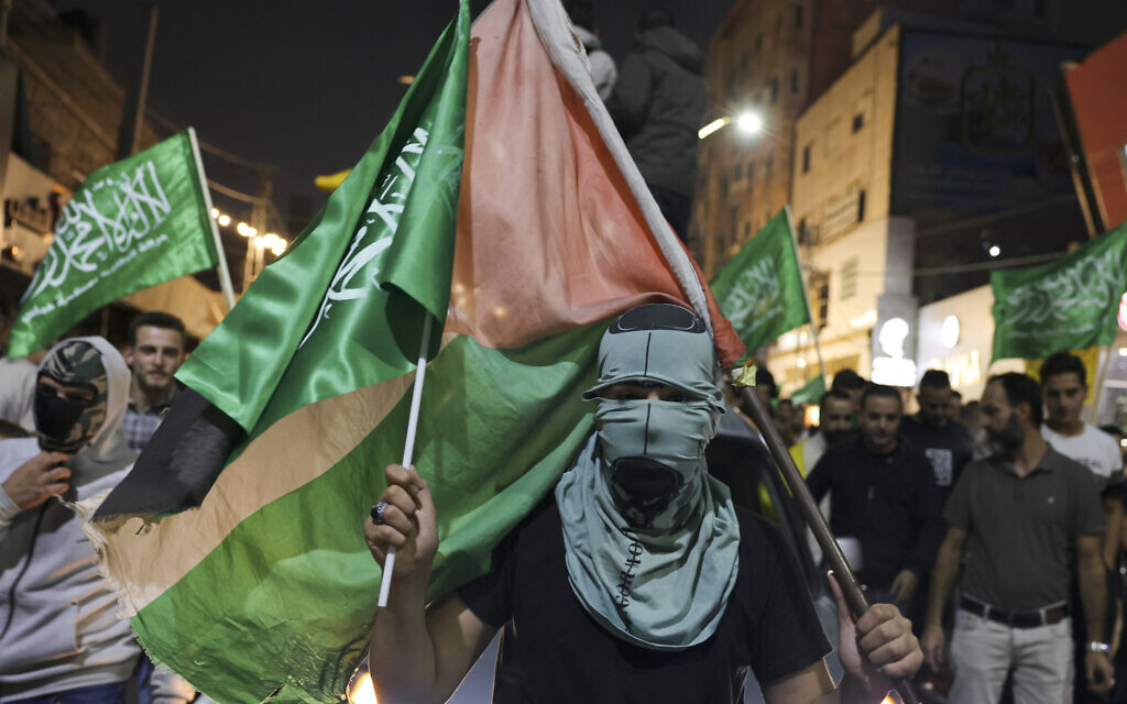 Des partisans des mouvements Fatah et Hamas brandissent des drapeaux du groupe terroriste palestinien lors d'une marche dans la ville d'Hébron, en Cisjordanie, le 11 octobre 2023 (Crédit : HAZEM BADER / AFP)