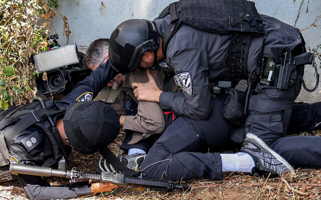 Les forces de sécurité viennent en aide à un journaliste pendant une alerte à la roquette dans la ville de Sderot, le 12 octobre 2023. (Crédit : Menahem KAHANA / AFP)