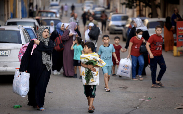Des Palestiniens transportant leurs affaires fuyant vers des zones plus sûres dans la ville de Gaza après des frappes aériennes israéliennes, le 13 octobre 2023. (Crédit : Mahmud Hams/AFP)