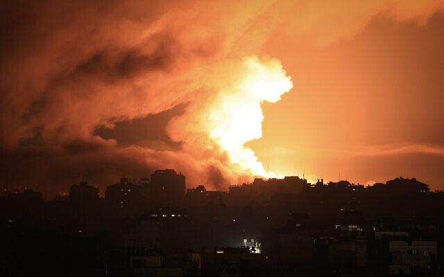 Du feu et de la fumée s’élevant au-dessus des bâtiments de la ville de Gaza lors d'une frappe aérienne israélienne, le 13 octobre 2023. (Crédit : Mahmud Hams/AFP)