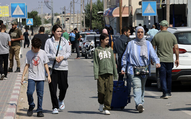Des personnes munies de passeports étrangers arrivant à la porte de Rafah avec l'espoir de traverser en Égypte alors que les frappes de représailles d'Israël sur la bande de Gaza se poursuivent, le 14 octobre 2023. (Crédit 
: Saïd Khatib/AFP)