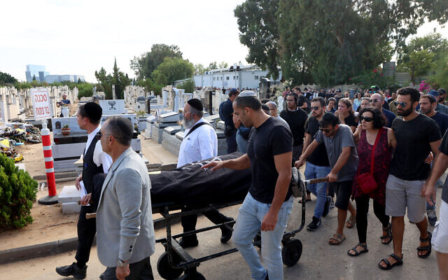 Ido Nagar pousse le chariot transportant le corps de son épouse Céline Ben David Nagar, citoyenne israélo-française tuée lors de l'attaque de la semaine dernière par des terroristes du Hamas en Israël, lors de ses funérailles à Holon, au sud de Tel Aviv, le 17 octobre 2023. (Crédit : GIL COHEN MAGEN / AFP)